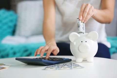 3 Dinge, die wohlhabende Menschen tun, um ihr Geld zu vermehren: Hand steckt Geld ins Sparschwein