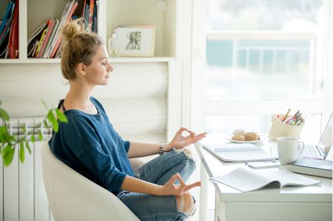 Achtsamkeitstraining: Frau sitzt am Schreibtisch und meditiert