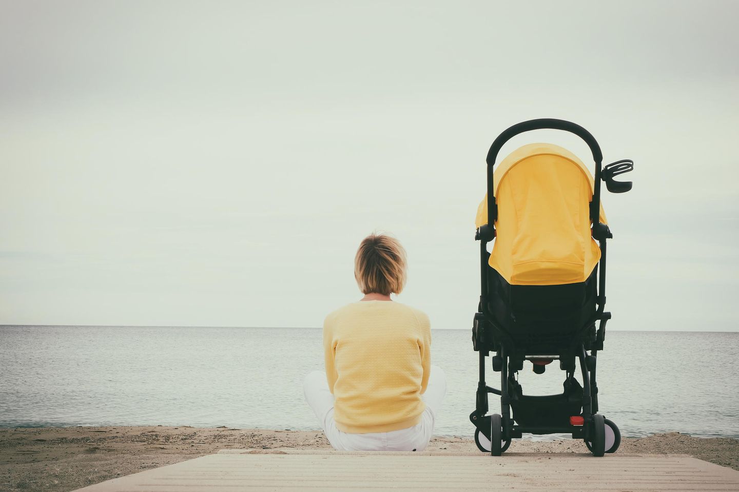 Kind alleine lassen: Mutter mit Kinderwagen am Strand