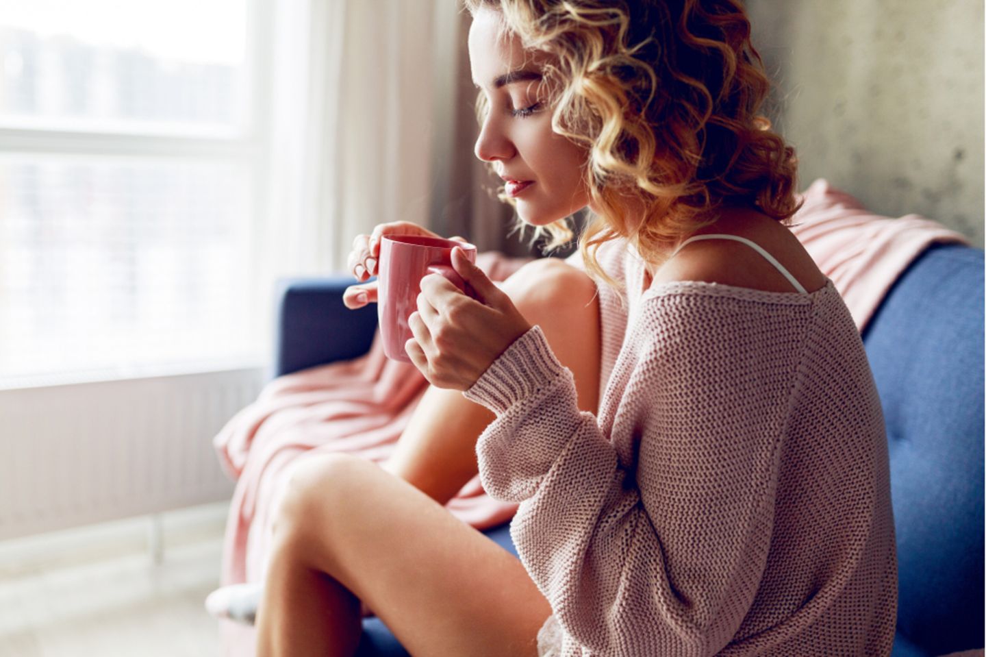Minderwertigkeitskomplexe: Frau trinkt Tee und sitzt auf der Couch