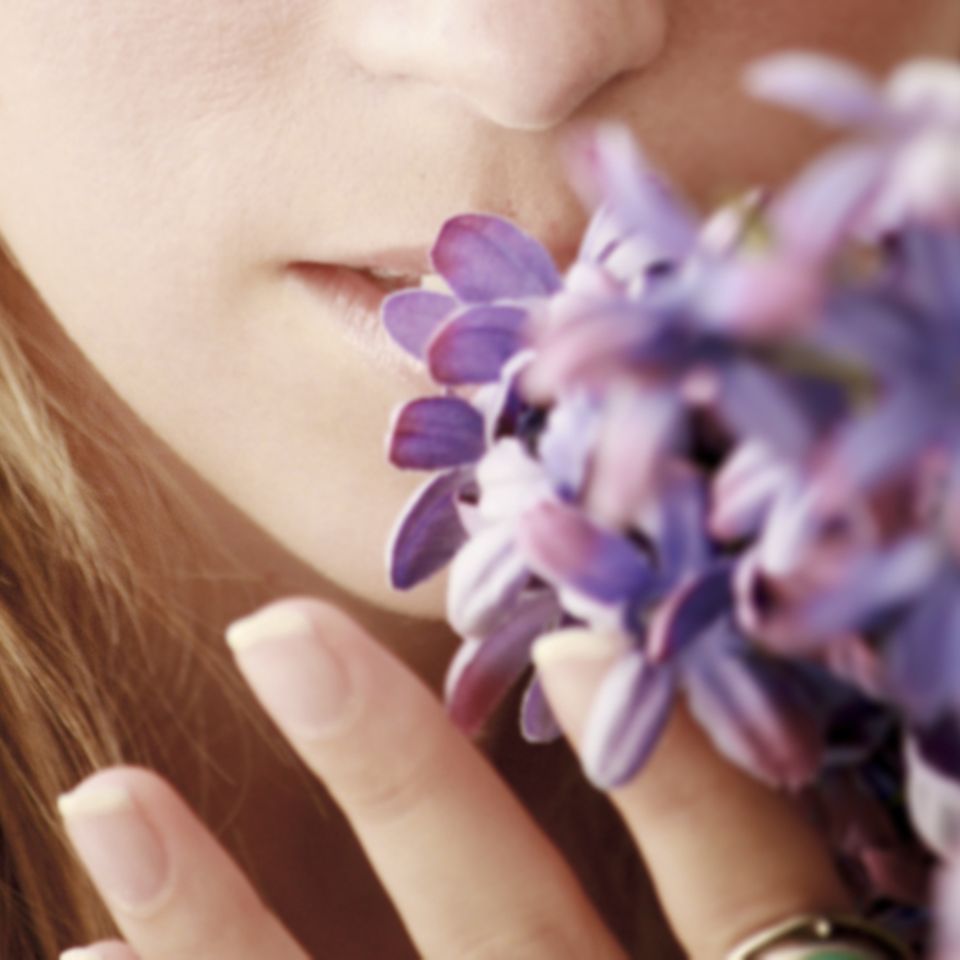 Geruchssinn: Frau riecht an Blumen
