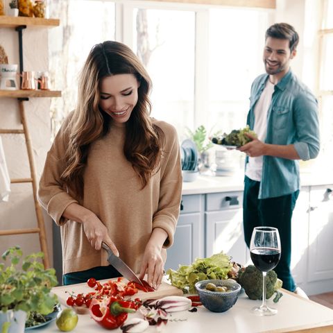 Küchengadgets: Paar am Kochen, Frau schneidet Gemüse, glückliches Paar in der Küche
