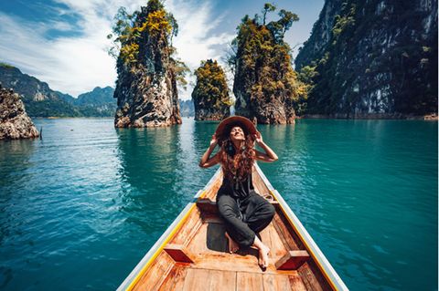 Huna: Glückliche Frau im Boot vor tropischer Landschaft.