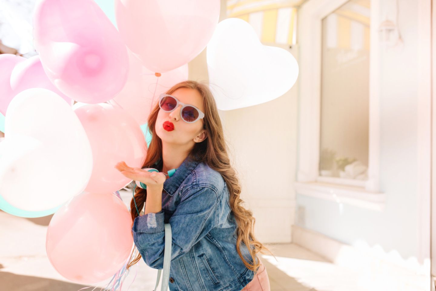 Emophilia: Frau hält Herzluftballons und macht einen Kussmund