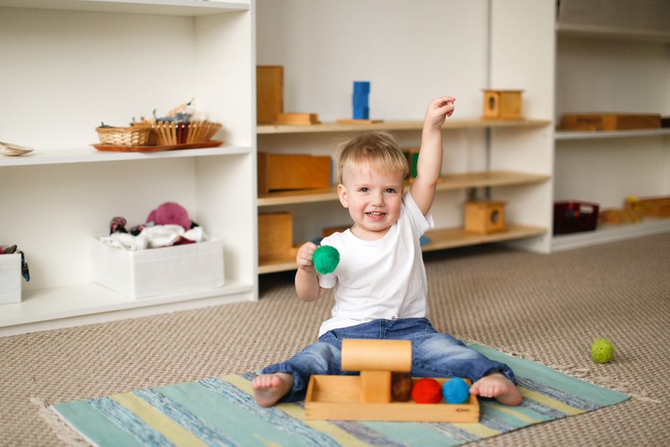 Montessori Kinderzimmer: Kind spielt mit Holzspielsachen