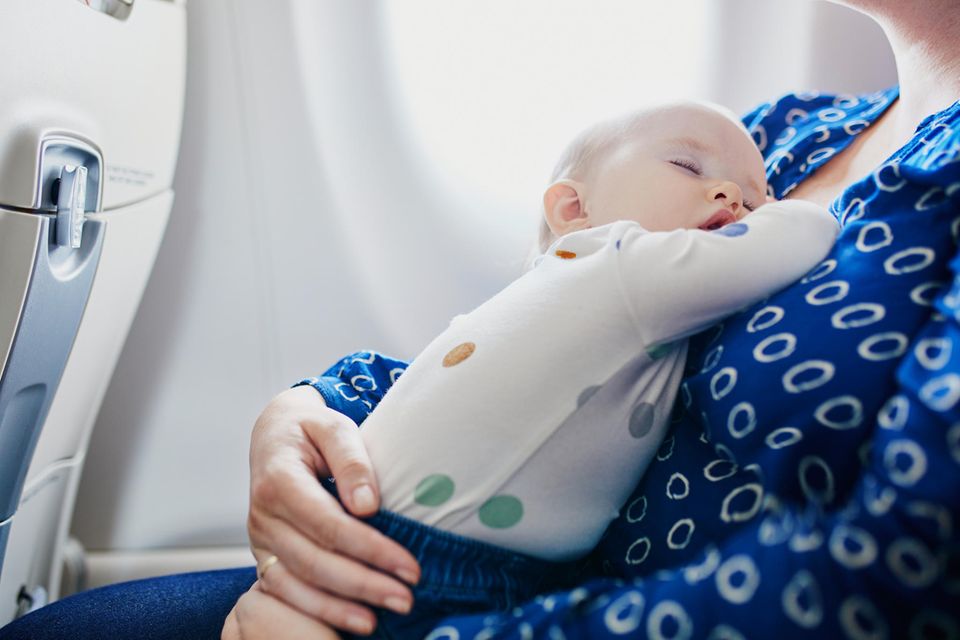 Fliegen mit Baby: Mutter sitzt mit Baby im Flugzeug