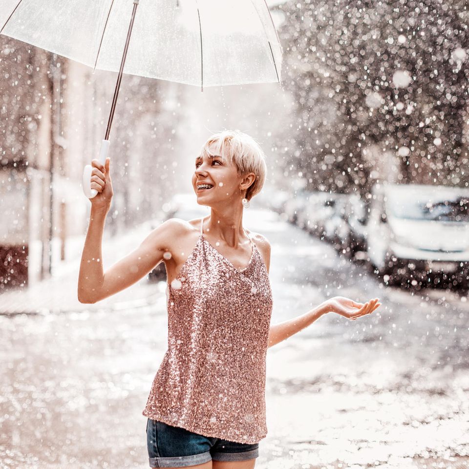 Horoskop: Eine leicht bekleidete Frau mit Schirm im Schnee
