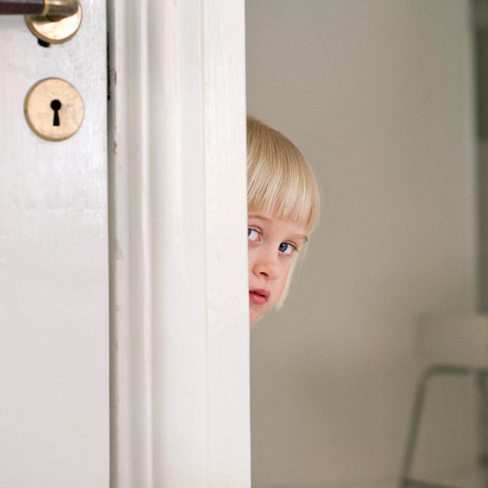 Kind schaut hinter Tür hervor