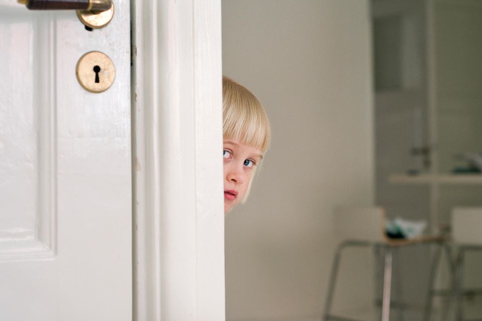 Kind schaut hinter Tür hervor