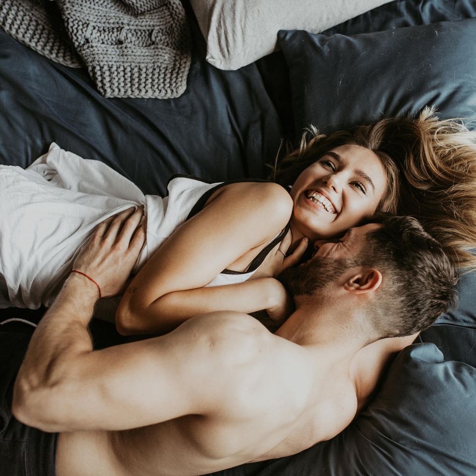 Sex mit dem Ex: Mann und Frau liegen lachend im Bett und umarmen sich