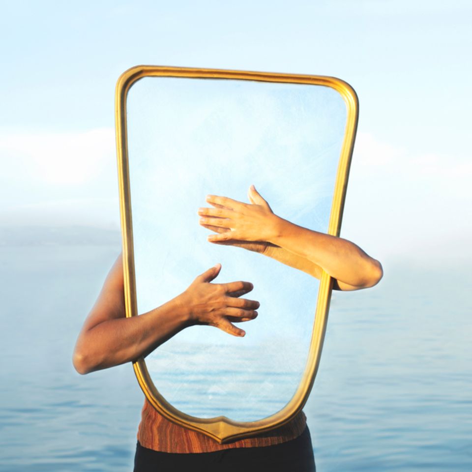 Selbstwahrnehmung: Frau hält einen Spiegel vor ihren Körper
