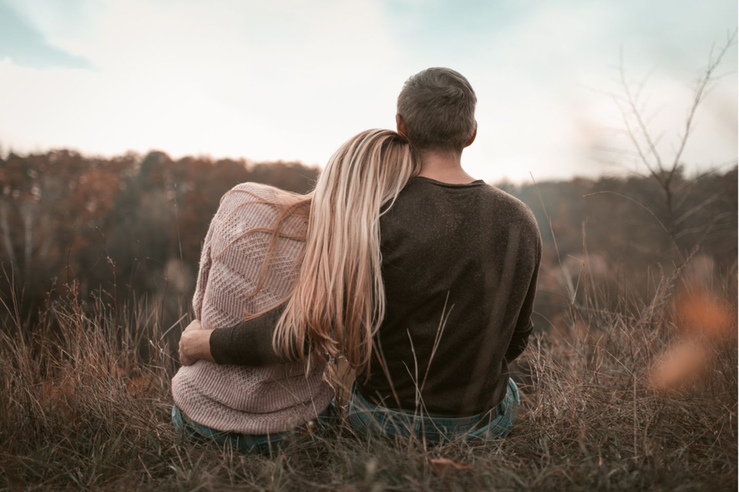 Emotionale Abhängigkeit: Frau und Mann sitzen im Gras nebeneinander