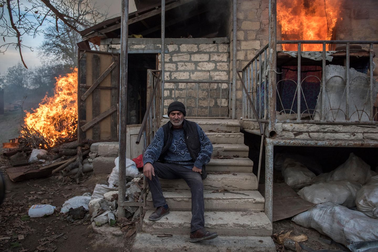 World Press Photo: Mann sitzt vor brennendem Haus