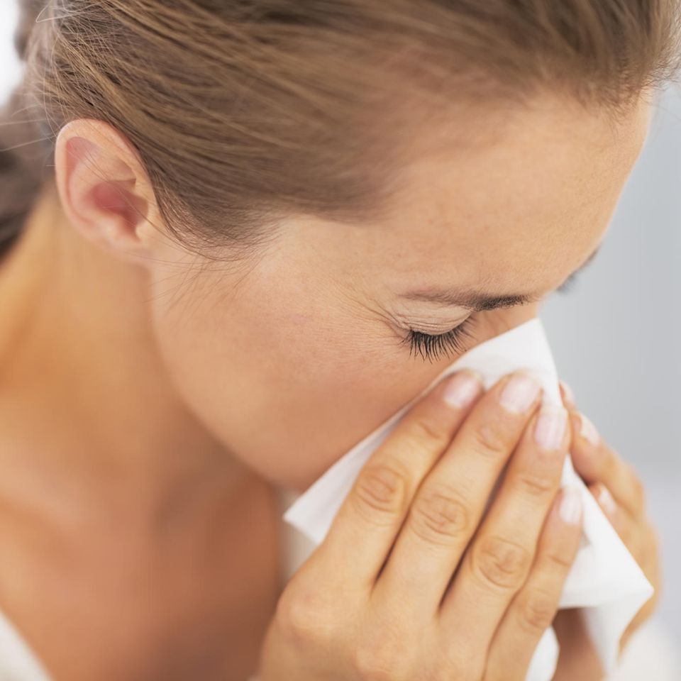 Allergie während Corona: Frau putzt ihre Nase