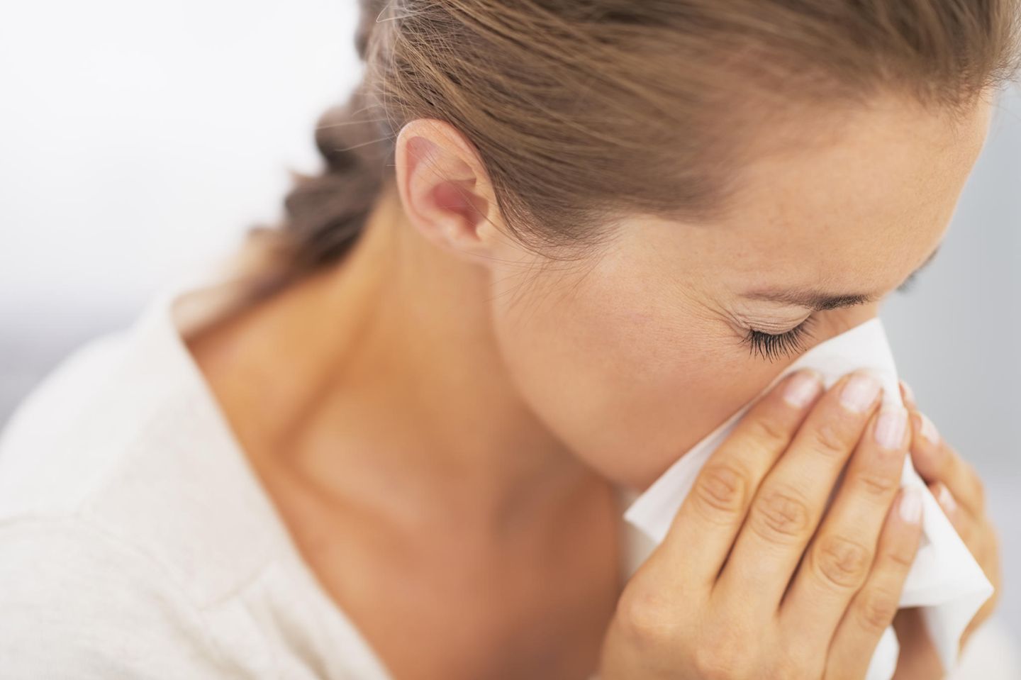 Allergie während Corona: Frau putzt ihre Nase