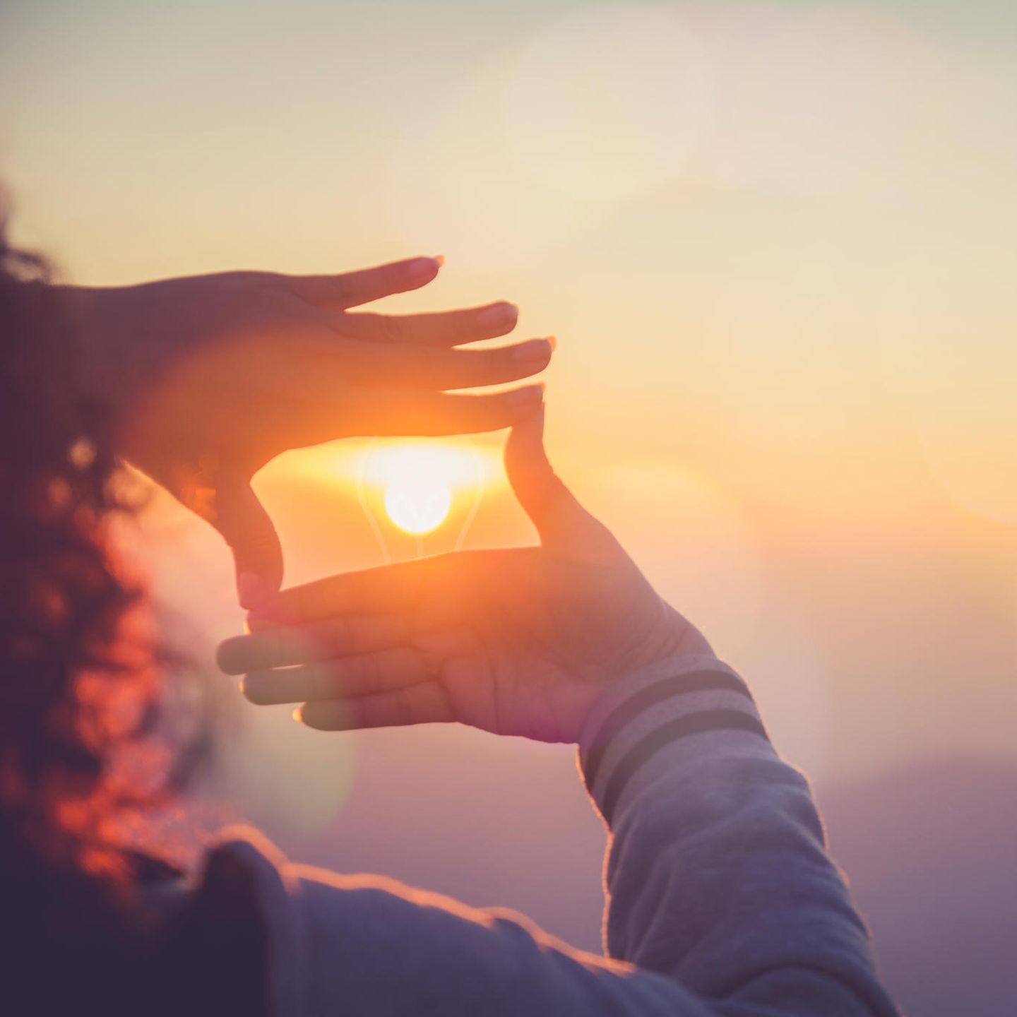 Horoskop: Eine Frau lässt die Sonne durch ihre Hände
