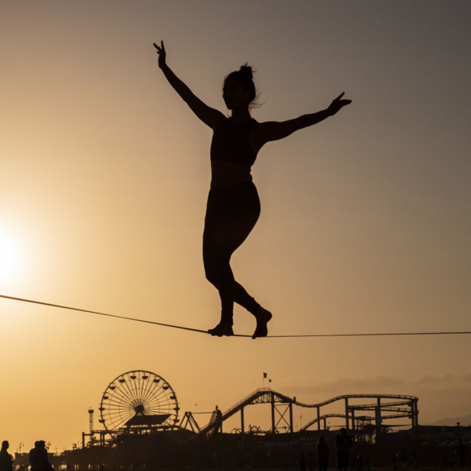 Ausgeglichenheit: Frau balanciert auf Seil