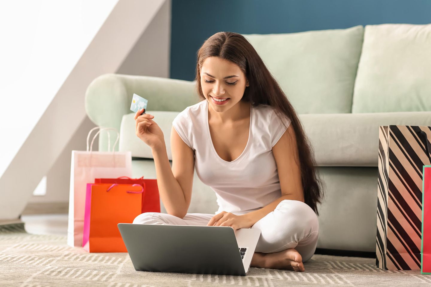 Frau mit Kreditkarte sitzt vor Laptop, Online Shopping