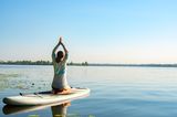 Horoskop: Eine Frau macht Yoga auf einem Surfbrett