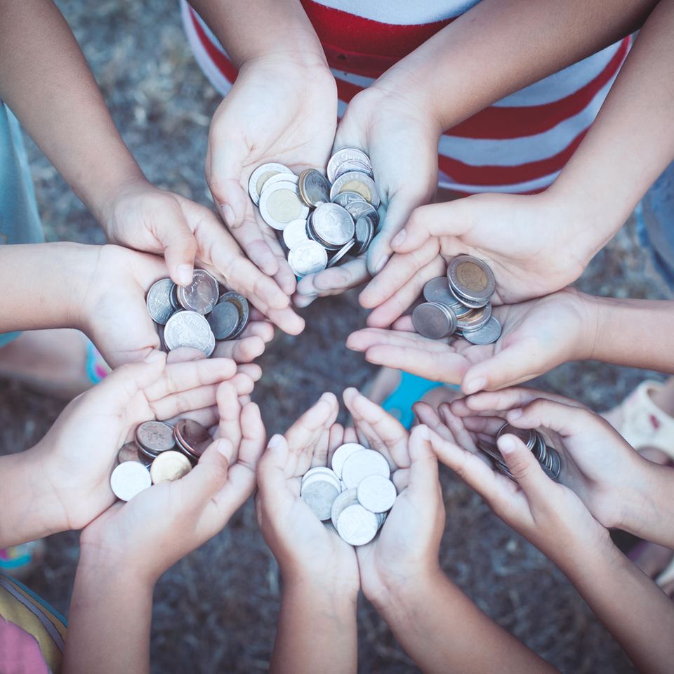 Umgang mit Geld: Kinder halten Münzen in den Händen