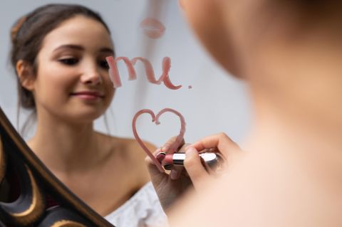 Selbstliebe: Frau malt Herz mit Lippenstift auf einen Spiegel