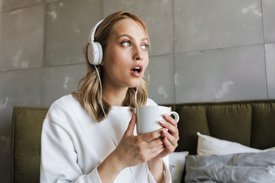 Akustische Illusion: Frau mit Kopfhörern lauscht konzentriert im Cafè