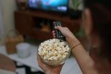 Auftankmoment: Frau mit Popcorn und Fernbedienung