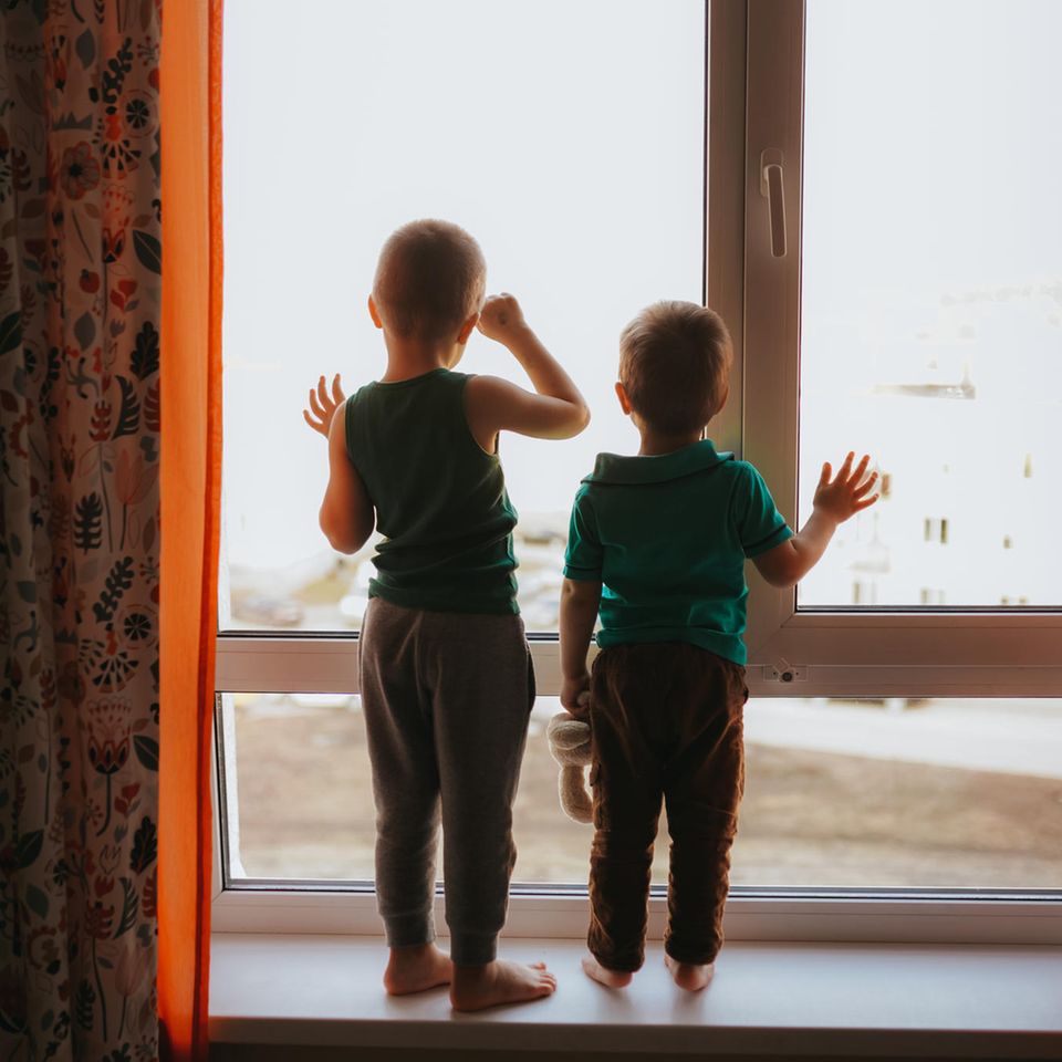 Armutsfalle Hartz4: 2 Kinder schauen durchs Fenster nach draußen