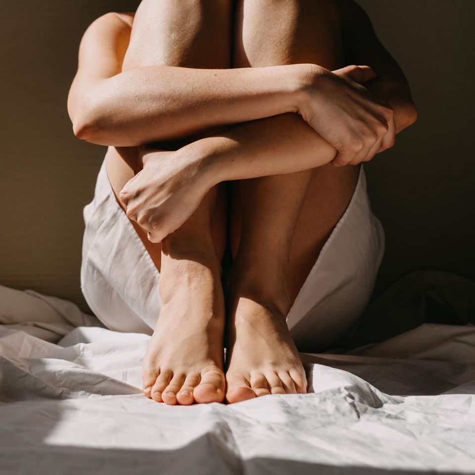 Fehlendes Selbstvertrauen: Frau sitzt auf dem Boden und umarmt ihre Beine
