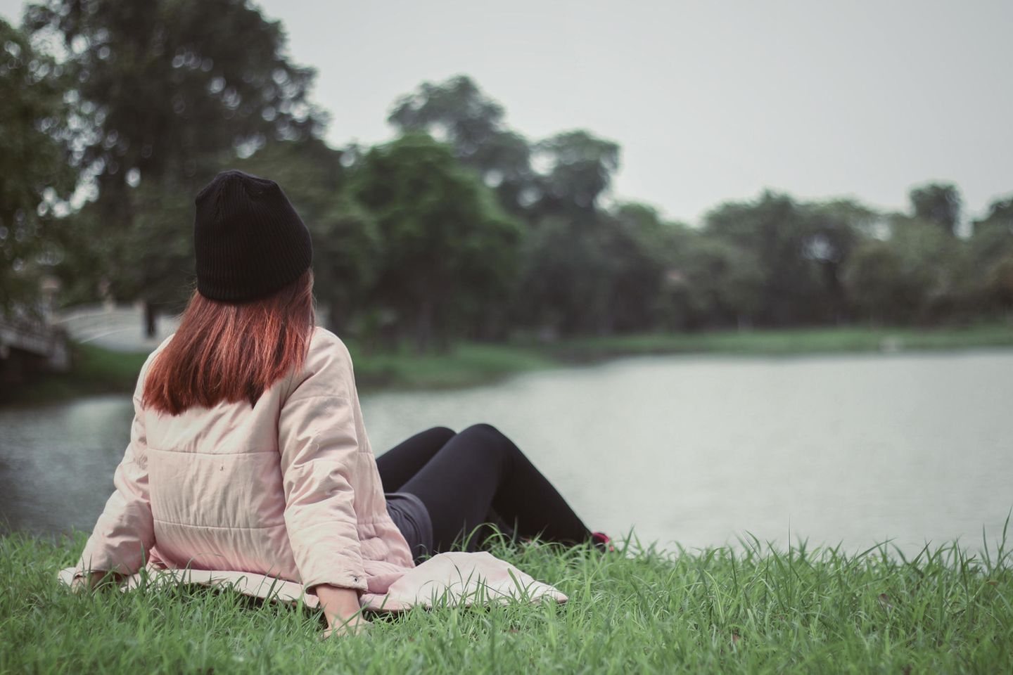 Beziehung: Eine junge Frau sitzt am See