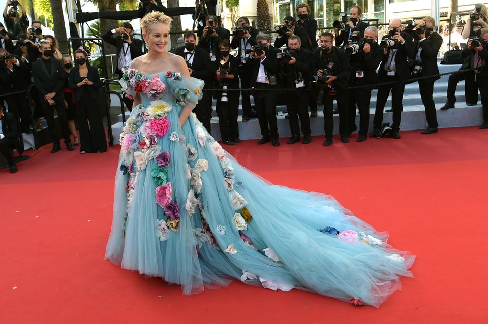 Für Schauspielerin Sharon Stone ist auf dem roten Teppich von Cannes mehr definitiv mehr! Ihr auffälliges Tüllkleid mit angesteckten Blüten stammt aus dem Hause Dolce & Gabanna und sorgt für geteilte Meinungen. Ihr Schmuck ist von Chopard.