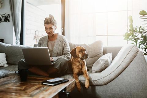 LinkedIn: Frau sitzt auf dem Sofa und schreibt auf ihrem Laptop
