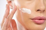 Hautpflege: Frau cremt sich das Gesicht ein
