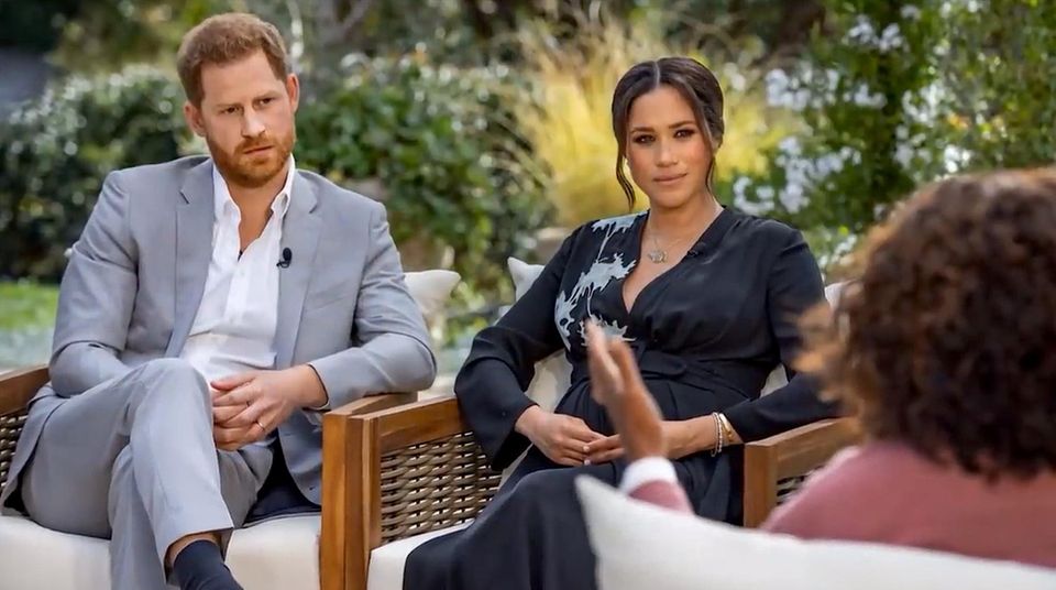 Prinz Harry und Meghan Markle sitzen bei dem Oprah Interview nebeneinander im Garten.