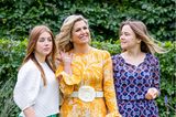 Royales Trio: Königin Máxima mit ihren Töchtern Prinzessin Alexia und Ariane herausgeputzt für einen sommerlichen Fototermin. Dabei setzt die holländische Königin auf ein gelbes gemustertes Kleid mit Volants und einem weißen Taillen-Gürtel.  