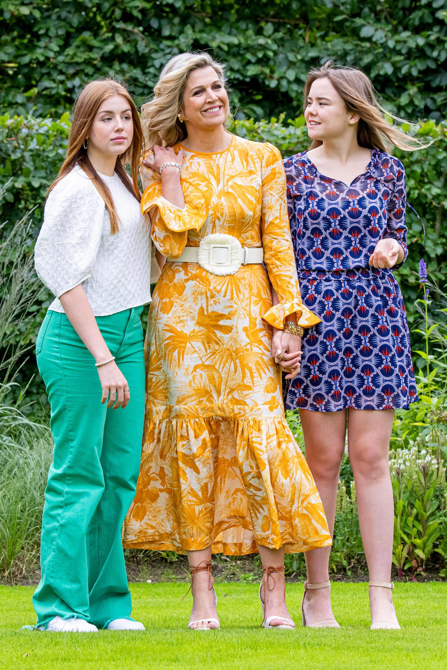 Royales Trio: Königin Máxima mit ihren Töchtern Prinzessin Alexia und Ariane herausgeputzt für einen sommerlichen Fototermin. Dabei setzt die holländische Königin auf ein gelbes gemustertes Kleid mit Volants und einem weißen Taillen-Gürtel.  