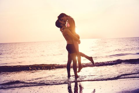 Sex im Urlaub: Mann hebt Frau am Strand hoch und küsst sie