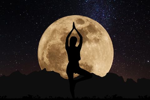 Horoskop: Umriss einer Frau, die vor dem Vollmond Yoga macht