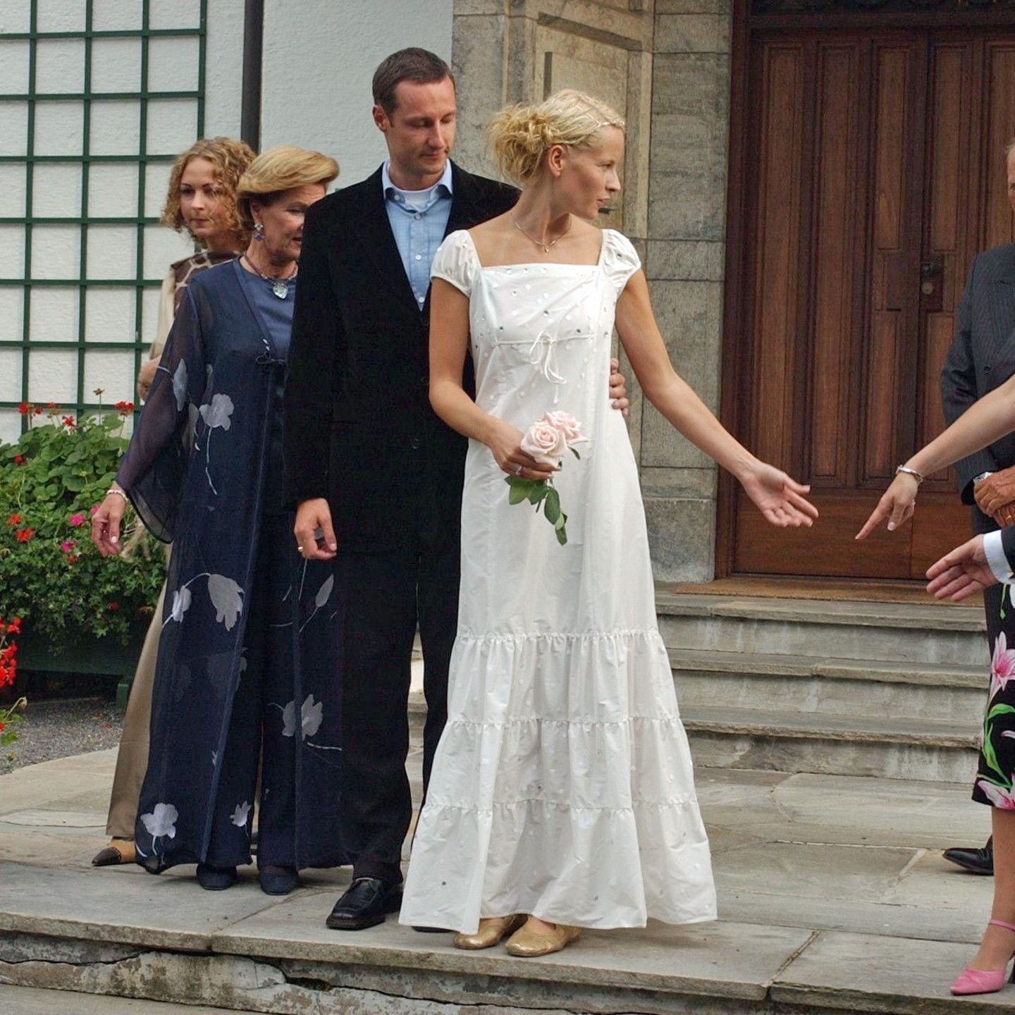 Schon am 23. August 2001, also zwei Tage vor ihrer Hochzeit mit Prinz Haakon, zeigte sich Mette-Marit in einem Kleid, das durchaus als legeres Brautkleid durchgehen könnte. Das weiße Dress mit Abnähern am Saum kombinierte sie zu goldenen Ballerinas. In Sachen Haarstyling setzte Mette-Marit auf einen tiefen Seitenscheitel und viele in die Haare eingeflochtene Bänder – so wie man es damals eben trug.