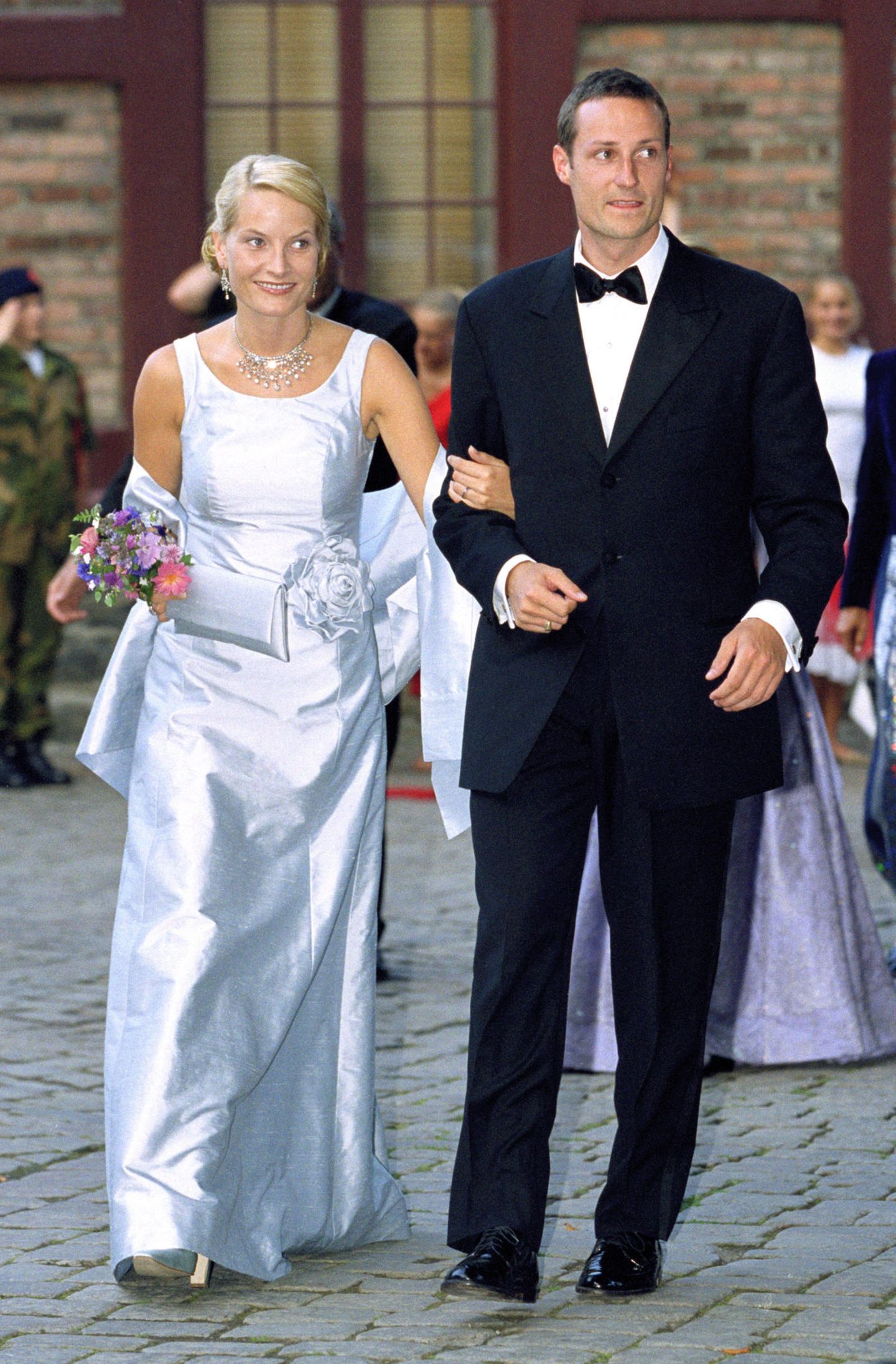 Einen Abend vor ihrer Hochzeit luden Mette-Marit und Prinz Haakon zu einem Galadinner auf Schloss Akershus ein. Die Braut in spe entschied sich für einen Brautkleid-inspirierten Look bestehend aus einem zartblauen Satindress mit farbig passendem Bolero und Blumenapplikation. Die Clutch in selbigem Blauton fügte sich harmonisch ins Bild. 
