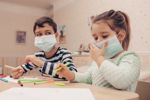 Zwei Kinder beim Malen mit medizinischen Masken.