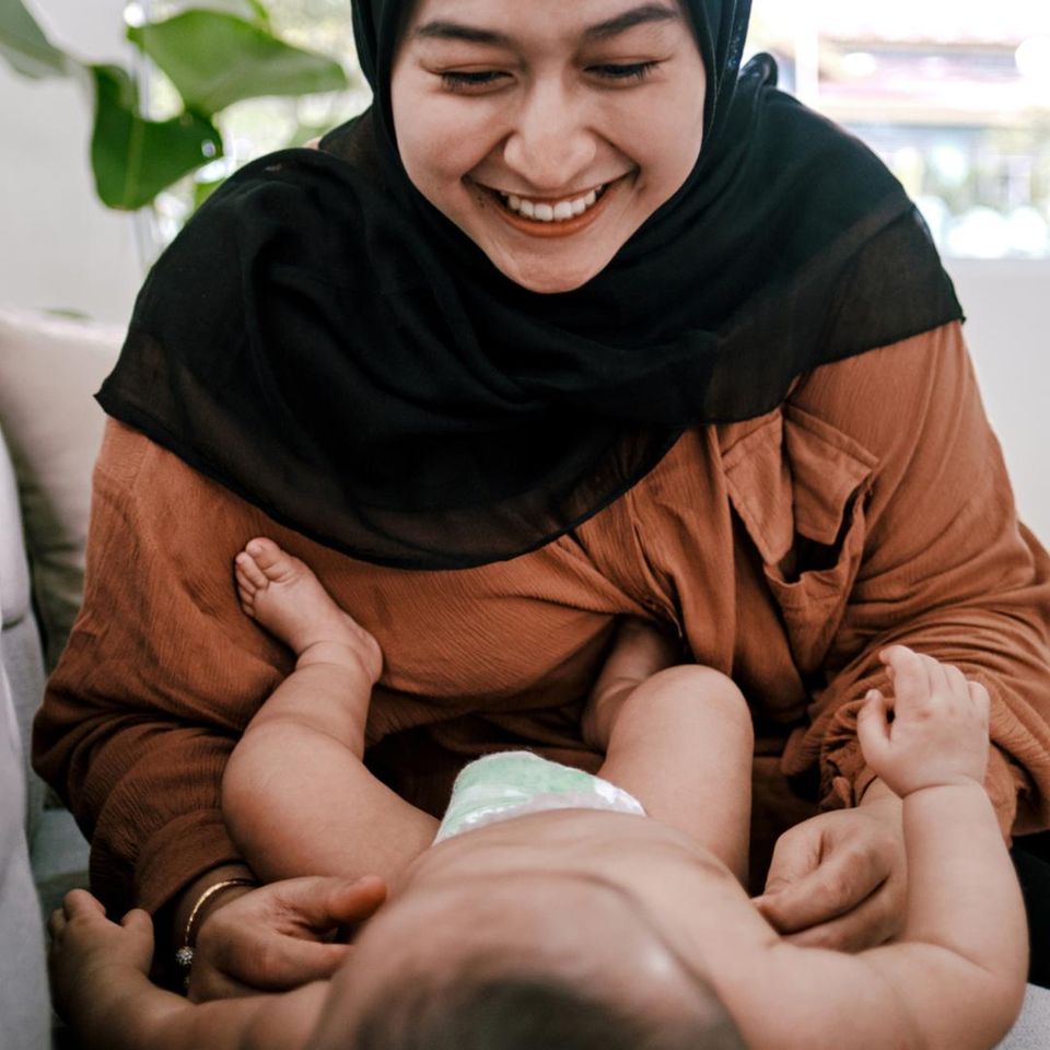 Postpartum Unfiltered: Frau lächelt Baby an