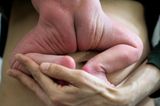 Postpartum Unfiltered: Hand hält Neugeborenes