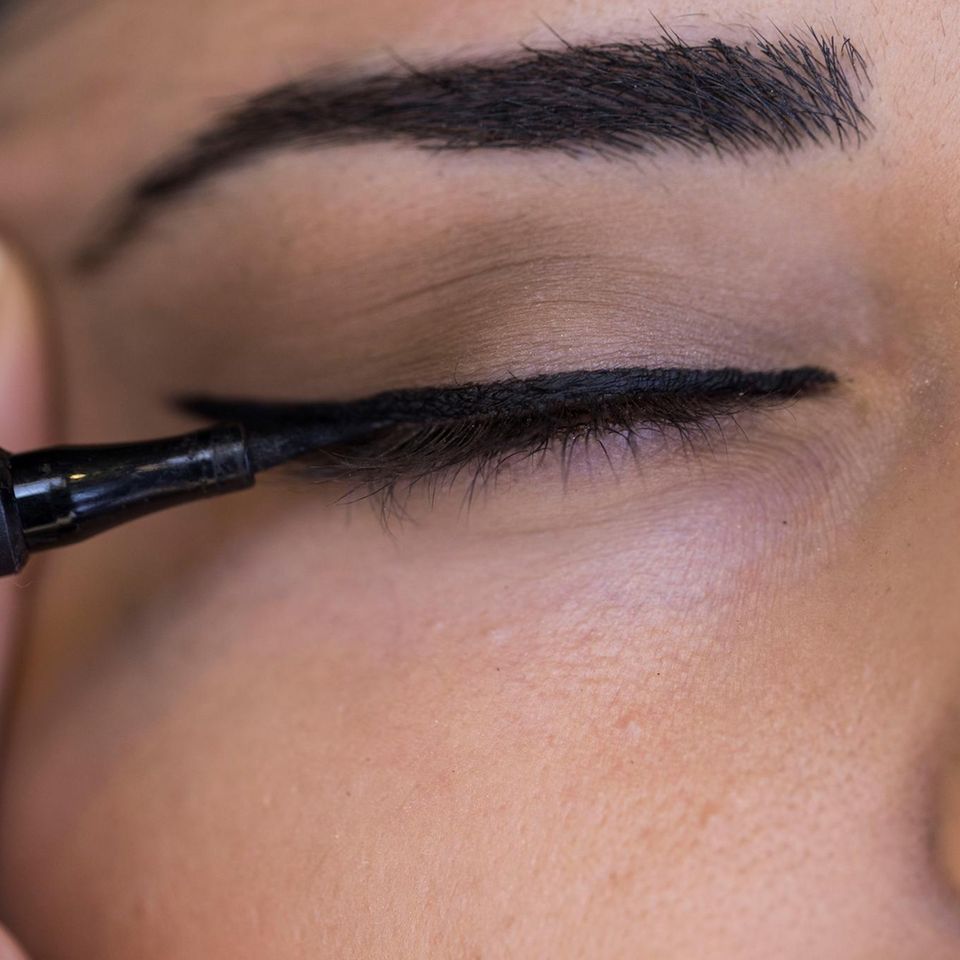 Eyeliner: Frau trägt schwarzen Eyeliner auf