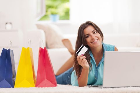 Frau mit Kreditkarte, Laptop und Einkaufstüten, Online-Shopping