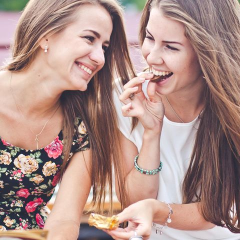 Zwei fröhliche Frauen essen Schokolade.
