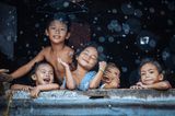 „Regenzeit“ – dieses Bild setzte sich beim "CEWE Photo Award 2021" unter 606.289 Einreichungen in der Kategorie „Menschen“ durch. Das Foto von Hartmut Schwarzbach zeigt Kinder in einer Wellblechhütte eines Armenviertels auf den Philippinen, die, wie es scheint, auch bei strömendem Regen ihre kindliche Unbeschwertheit nicht verloren haben.