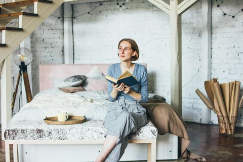 Psychologie: Frau sitzt nachdenklich auf dem Bett