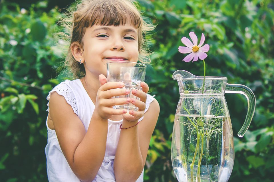 Trinkwasser: Mädchen hält Wasserglas in der Hand