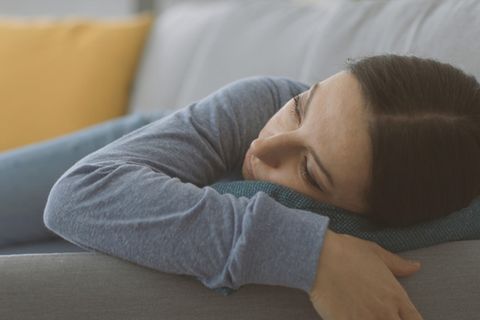 Stellvertreter-Burnout: Frau auf dem Sofa, starrt müde in die Luft